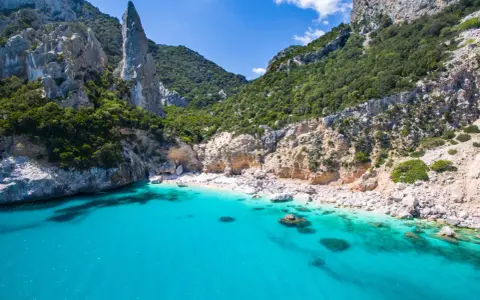 Spiaggia rosa di Budoni, incastonata tra scogliere imponenti e un mare cristallino.