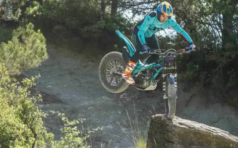 Un pilota esperto con una Honda Montesa compie un salto su un masso in un percorso fuoristrada.