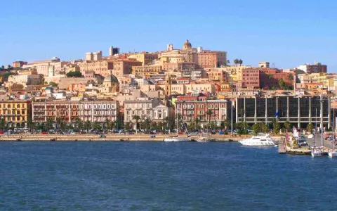Vista del quartiere Marina di Cagliari con palazzi colorati, palme e yacht ormeggiati.