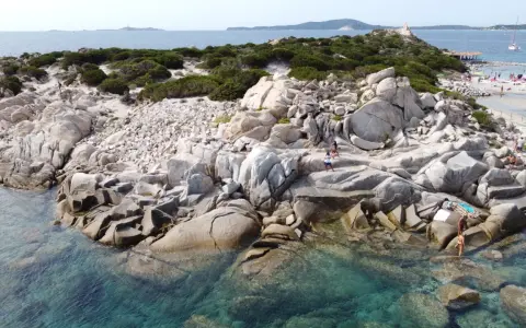 Scogliere rocciose e acque cristalline sulle spiagge a Villasimius. Turisti esplorano la costa selvaggia e si godono il sole.