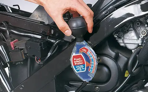 Controllo del liquido di raffreddamento a liquido moto con un densimetro. La mano tiene lo strumento per verificare la protezione antigelo.