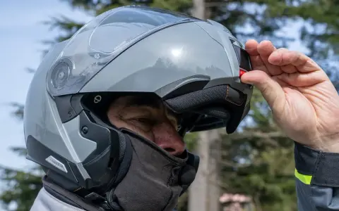 Uomo con casco modulare grigio, pronto per un viaggio in moto. Goditi la strada con questi caschi più silenziosi.