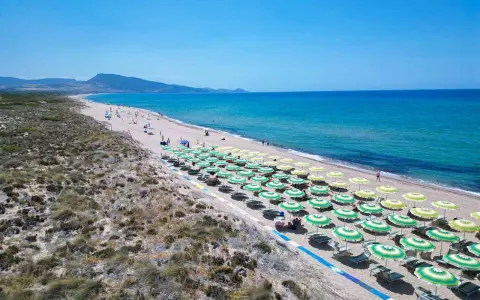 Spiaggia di Badesi: file di ombrelloni verdi e gialli, mare azzurro e dune sabbiose. Cosa vedere in questo paradiso.