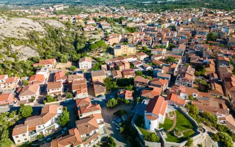 Vista aerea del centro storico di Arzachena, con le sue case dai tetti rossi e la chiesa in primo piano.