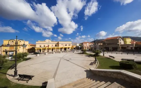 Piazza di San Giovanni Suergiu con edifici gialli e cielo azzurro.