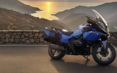 Moto blu parcheggiata su un promontorio con vista sul mare al tramonto. La corretta pressione gomme moto è fondamentale per un viaggio sicuro.