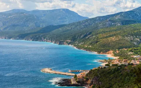 Vista panoramica di Cala Gonone, dove il blu intenso del mare incontra la costa frastagliata e le verdi montagne.