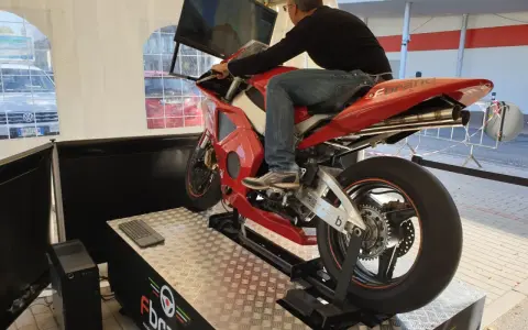 Uomo su una moto rossa da corsa, seduto su un simulatore di guida. Un'esperienza di guida virtuale con un sag moto.