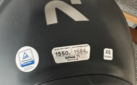 Casco nero con logo R argentato. Etichette indicano peso, modello RPHA 71, certificazione e taglia XS. Sul casco possono essere applicati adesivi.