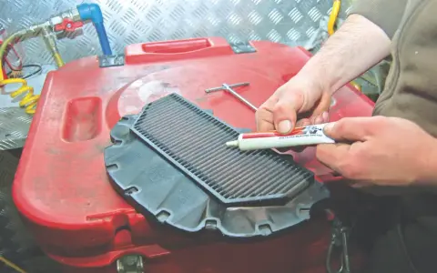 Applicazione di grasso sigillante sul bordo del filtro aria moto per una corretta pulizia e manutenzione.
