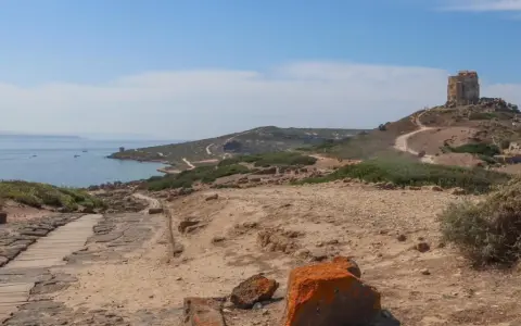 Torre aragonese su un colle roccioso, con rovine antiche e mare sullo sfondo, un paesaggio suggestivo di Tharros, Sardegna.