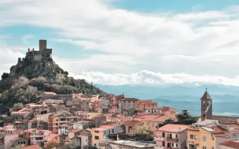 Borgo medievale di Burgos, Sardegna, con castello in rovina su uno sperone roccioso e case colorate a valle.