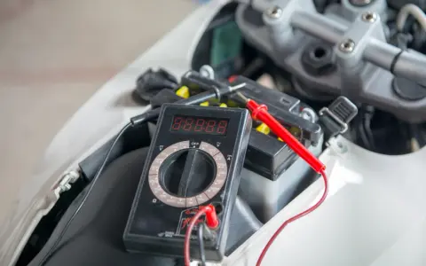 Multimetro collegato alla batteria della moto per verificarne lo stato prima di staccare la batteria moto inverno.