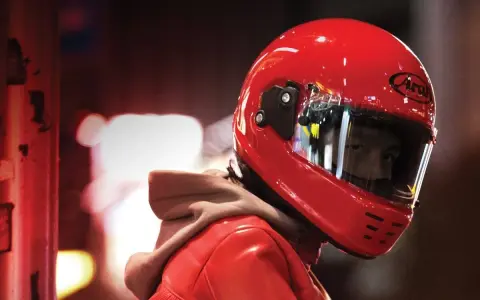 Un motociclista indossa un casco integrale rosso brillante, pronto per la strada.