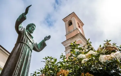 Statua di San Francesco con campanile e fiori. Il **Nuoro significato** di questo luogo è legato alla spiritualità e alla natura.