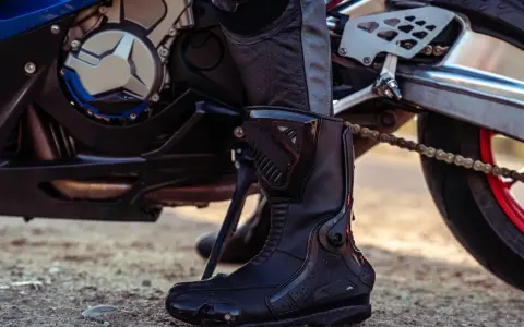Stivale da motociclista in pelle nera, con protezioni rigide e suola robusta, pronto per l'avventura.