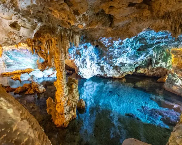 Stalattiti e stalagmiti illuminano le **grotte di Ispinigoli**, con un lago sotterraneo dalle acque cristalline e turchesi.