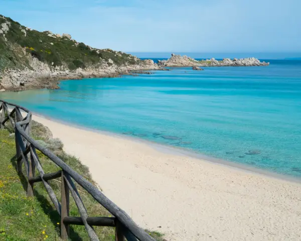 Una splendida spiaggia rena bianca bagnata da un mare cristallino. La vegetazione mediterranea e le rocce scolpite dal vento completano il paesaggio.