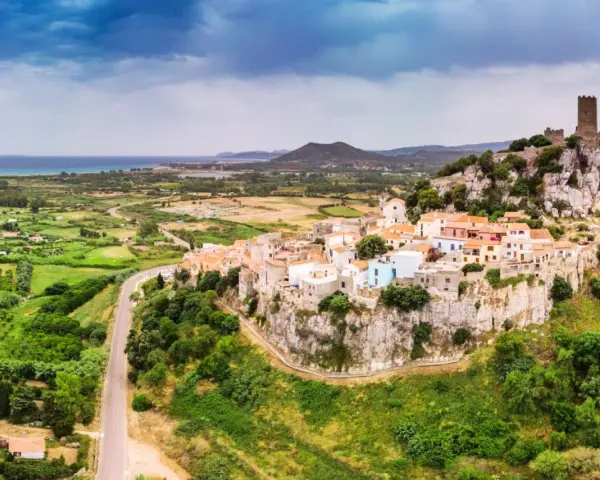 Borgo arroccato su una rupe con un castello medievale, affacciato su un paesaggio verdeggiante e il mare. La **posada dove si trova** è un gioiello incastonato nella roccia.