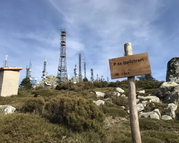 Segnale in legno a Punta Balistreri, m. 1360, con torri di telecomunicazioni sullo sfondo.
