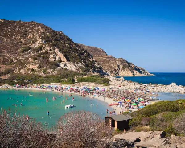 Una giornata di sole a Punta Molentis beach, con acque cristalline, sabbia dorata e tante persone che si godono il mare.