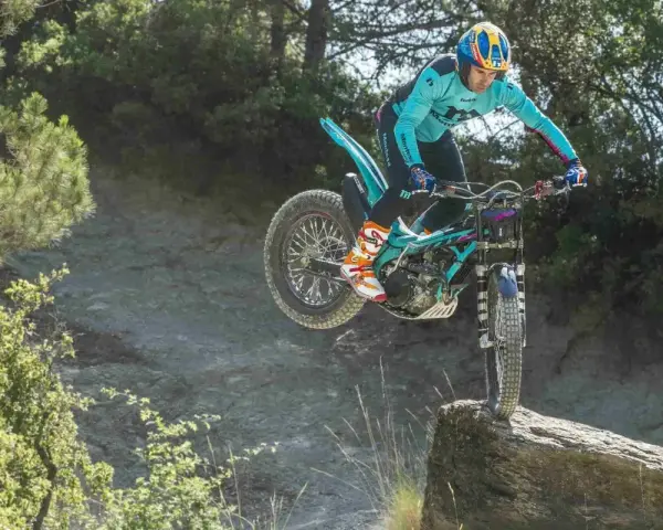 Un pilota esperto con una Honda Montesa compie un salto su un masso in un percorso fuoristrada.