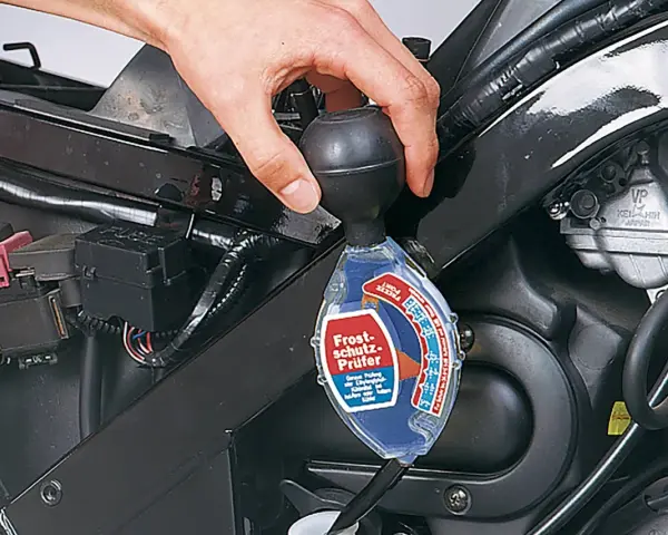 Controllo del liquido di raffreddamento a liquido moto con un densimetro. La mano tiene lo strumento per verificare la protezione antigelo.