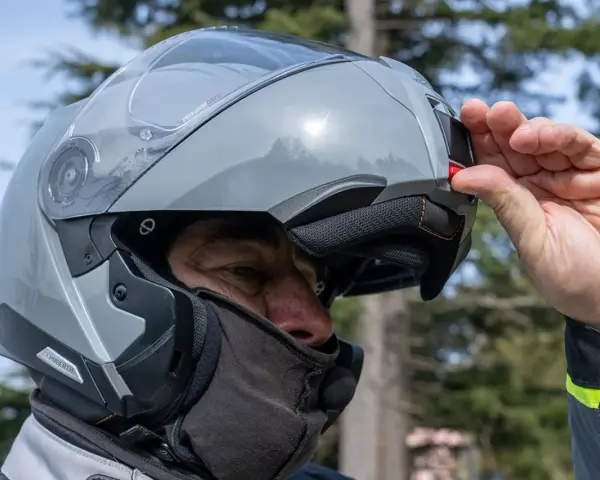 Uomo con casco modulare grigio, pronto per un viaggio in moto. Goditi la strada con questi caschi più silenziosi.