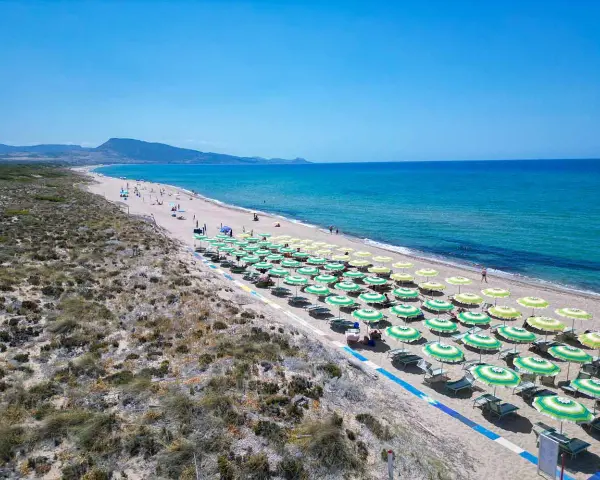 Spiaggia di Badesi: file di ombrelloni verdi e gialli, mare azzurro e dune sabbiose. Cosa vedere in questo paradiso.