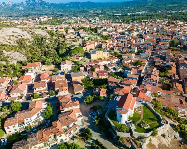 Vista aerea del centro storico di Arzachena, con le sue case dai tetti rossi e la chiesa in primo piano.