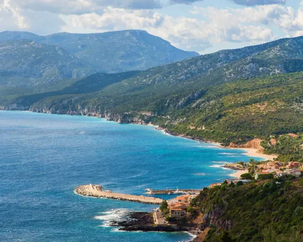 Vista panoramica di Cala Gonone, dove il blu intenso del mare incontra la costa frastagliata e le verdi montagne.