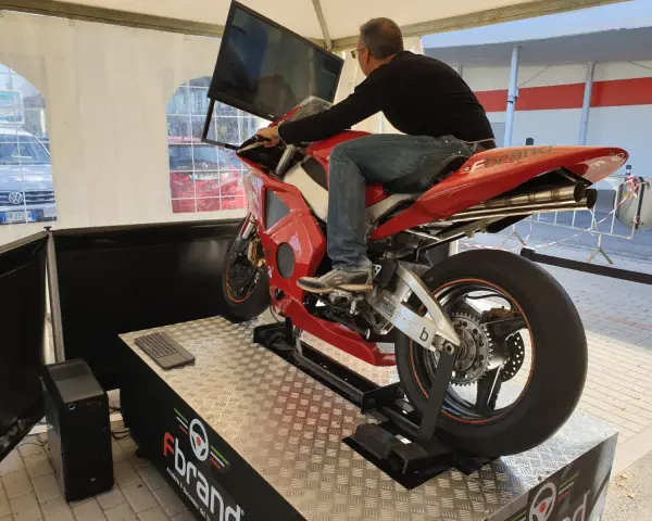 Uomo su una moto rossa da corsa, seduto su un simulatore di guida. Un'esperienza di guida virtuale con un sag moto.