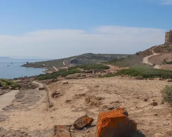 Torre aragonese su un colle roccioso, con rovine antiche e mare sullo sfondo, un paesaggio suggestivo di Tharros, Sardegna.
