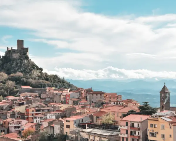 Borgo medievale di Burgos, Sardegna, con castello in rovina su uno sperone roccioso e case colorate a valle.