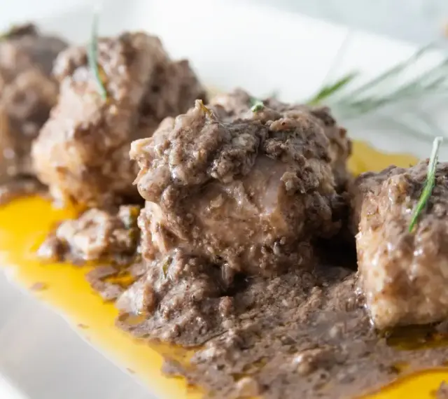 Burrida cagliaritana: bocconcini di pesce in salsa scura e dorata, guarniti con rosmarino.