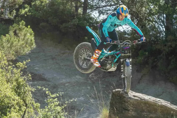 Un pilota esperto con una Honda Montesa compie un salto su un masso in un percorso fuoristrada.
