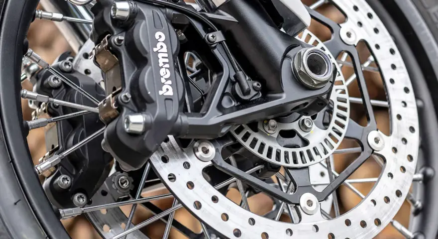 Primo piano della pinza freno Brembo e del disco forato, dettagli per la sostituzione pastiglie freni moto.