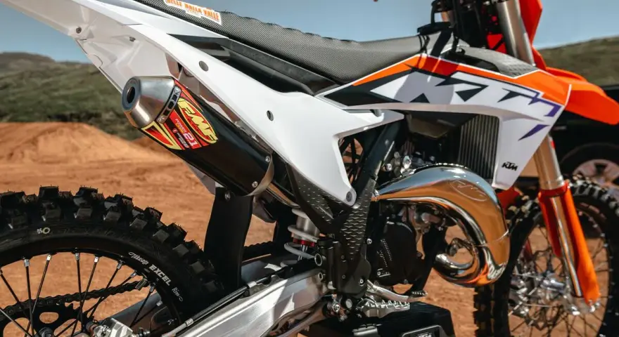 Scarico FMF su KTM arancione e bianca. La moto da cross, con il suo motore 2t, è pronta per la pista.