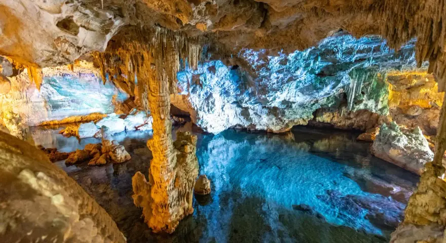 Stalattiti e stalagmiti illuminano le **grotte di Ispinigoli**, con un lago sotterraneo dalle acque cristalline e turchesi.