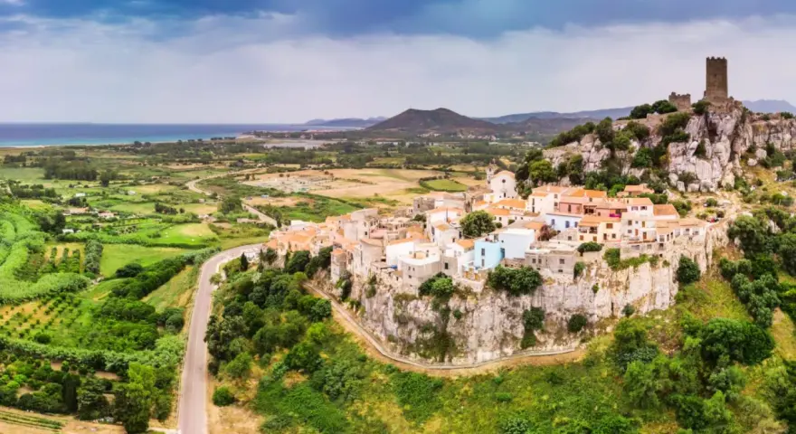 Borgo arroccato su una rupe con un castello medievale, affacciato su un paesaggio verdeggiante e il mare. La **posada dove si trova** è un gioiello incastonato nella roccia.