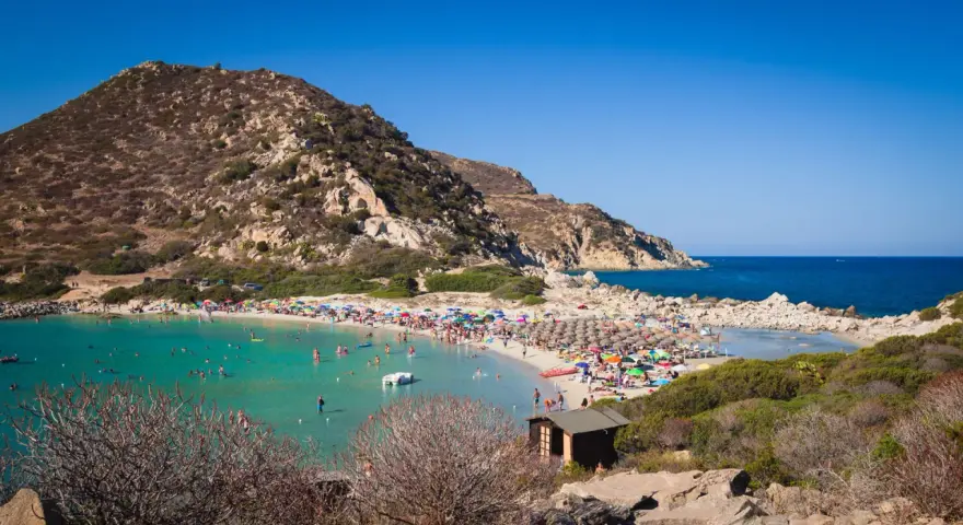 Una giornata di sole a Punta Molentis beach, con acque cristalline, sabbia dorata e tante persone che si godono il mare.