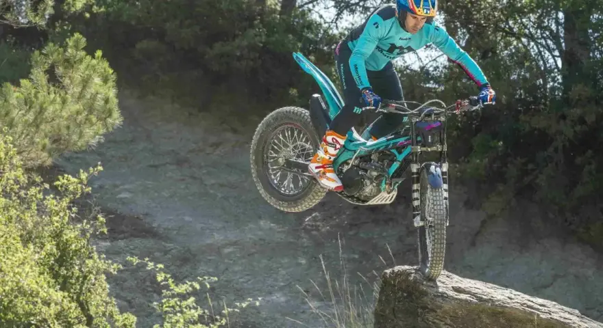 Un pilota esperto con una Honda Montesa compie un salto su un masso in un percorso fuoristrada.