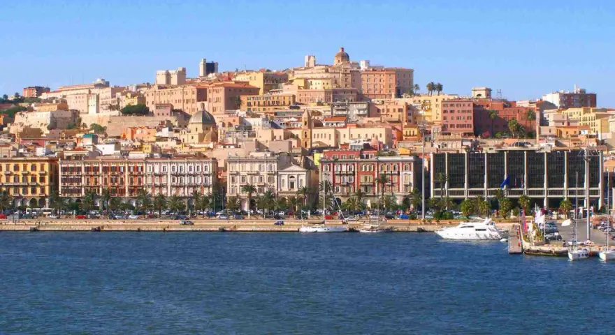 Vista del quartiere Marina di Cagliari con palazzi colorati, palme e yacht ormeggiati.