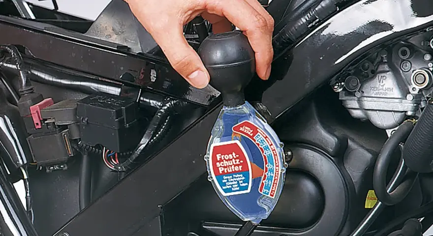 Controllo del liquido di raffreddamento a liquido moto con un densimetro. La mano tiene lo strumento per verificare la protezione antigelo.