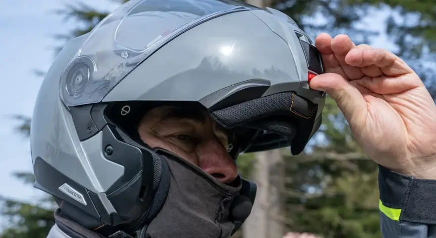 Uomo con casco modulare grigio, pronto per un viaggio in moto. Goditi la strada con questi caschi più silenziosi.