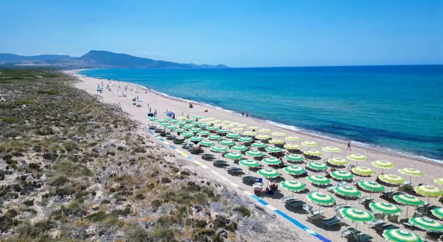 Spiaggia di Badesi: file di ombrelloni verdi e gialli, mare azzurro e dune sabbiose. Cosa vedere in questo paradiso.