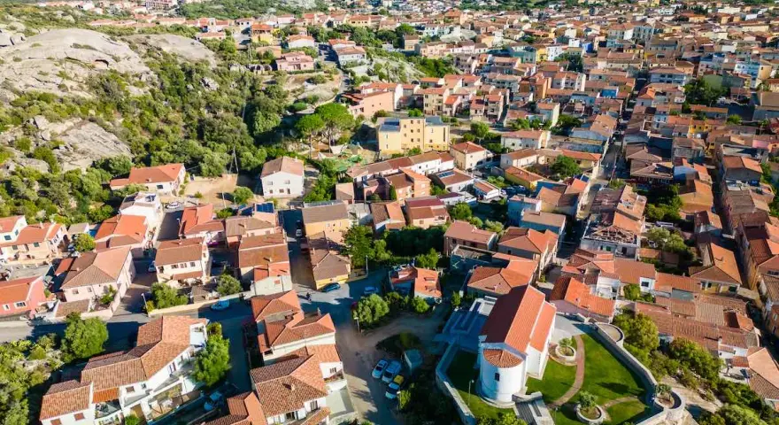 Vista aerea del centro storico di Arzachena, con le sue case dai tetti rossi e la chiesa in primo piano.