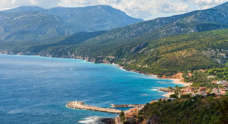 Vista panoramica di Cala Gonone, dove il blu intenso del mare incontra la costa frastagliata e le verdi montagne.
