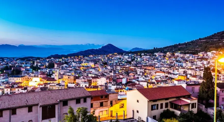 Vista serale di Cala Gonone, con luci accese tra le case. Perfetto per scoprire cosa fare la sera.