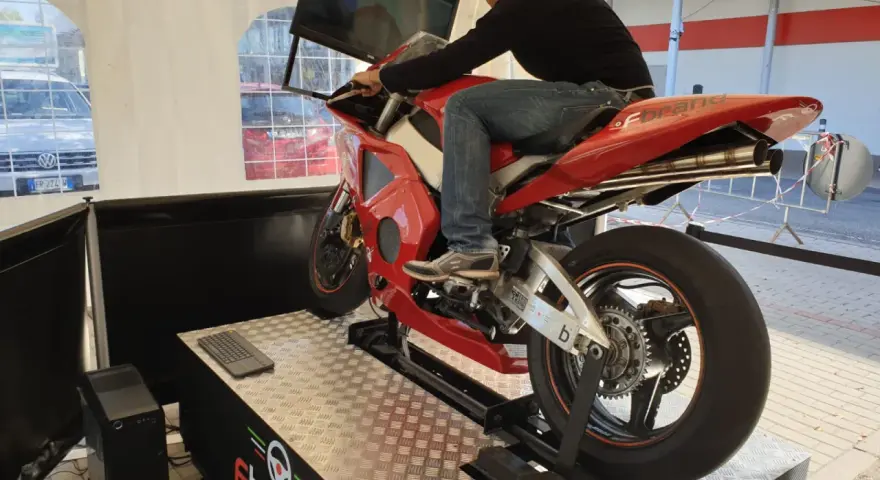 Uomo su una moto rossa da corsa, seduto su un simulatore di guida. Un'esperienza di guida virtuale con un sag moto.